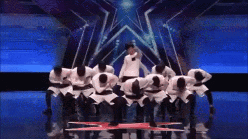 a group of people are kneeling down on a stage in front of a star .