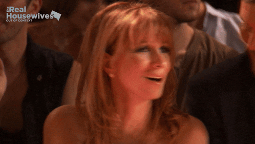 a woman sitting in a crowd with the real housewives logo on the bottom