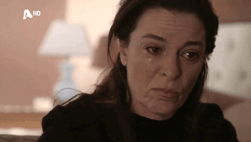 a woman with a tear running down her face is sitting on a couch .