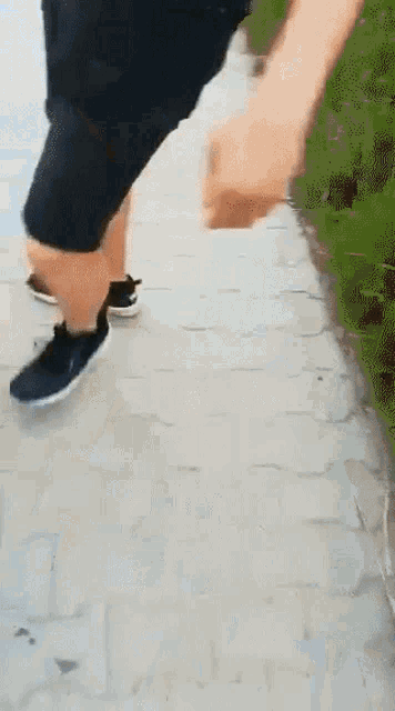 a person is walking down a sidewalk wearing shorts and sneakers .