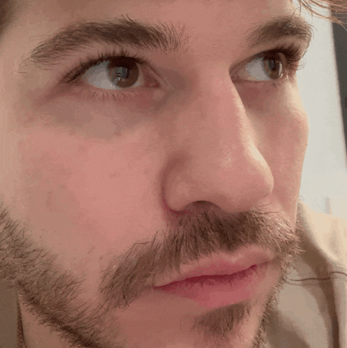 a close up of a man 's face with a beard and red lips