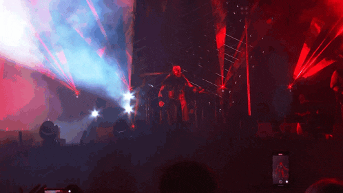 a man in a mask is playing a guitar on stage in front of a crowd