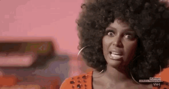 a woman with a large afro is wearing hoop earrings and making a funny face .
