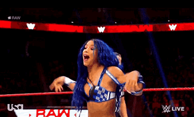 a female wrestler is dancing in a wrestling ring while a referee watches .