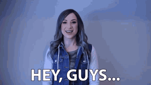 a woman in a denim jacket is giving a peace sign and saying hey guys