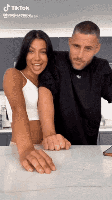 a man and a woman are standing next to each other with their arms outstretched .