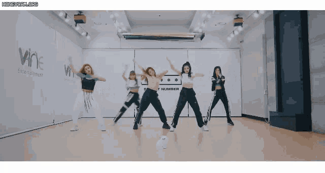 a group of girls are dancing in front of a wall that says t number