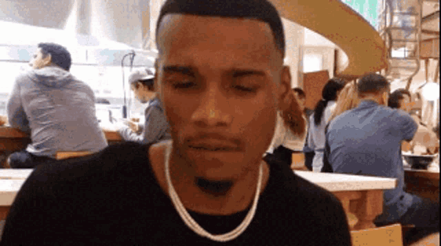a man sitting at a table with his eyes closed in a restaurant