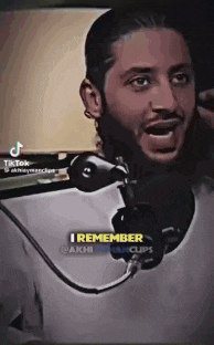 a man with a beard is talking into a microphone and says `` i remember '' .