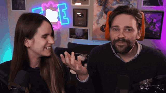 a man and a woman are standing in front of a neon sign that says e