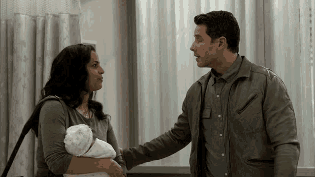 a man and a woman are standing next to each other holding a baby