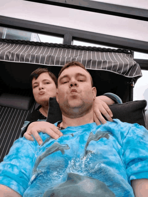 a man wearing a blue shirt with dolphins on it kisses a girl