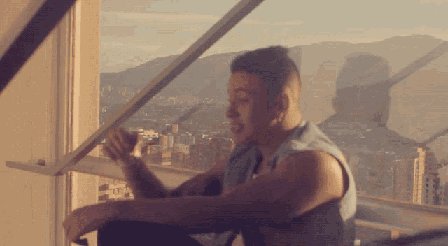 a man sitting on a balcony looking out a window