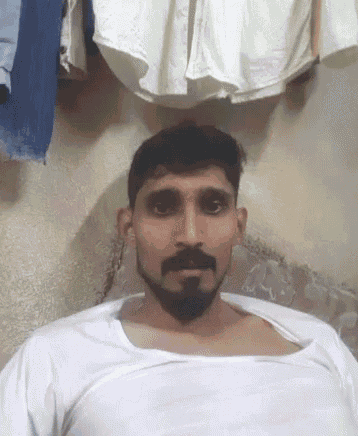 a man with a beard is wearing a white tank top .