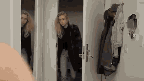 a woman is standing in a doorway next to a man in a coat .
