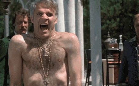 a man without a shirt is wearing a gold chain around his neck and shouting .