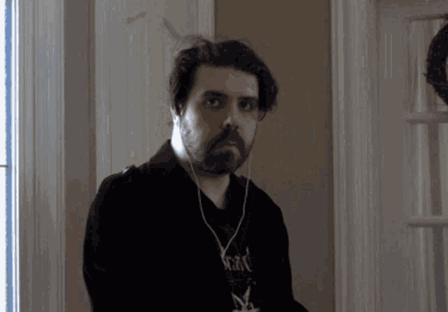 a man with a beard wearing ear buds and a shirt that says ' slayer ' on it