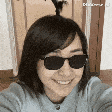 a woman wearing sunglasses and a sweater is smiling and taking a selfie .