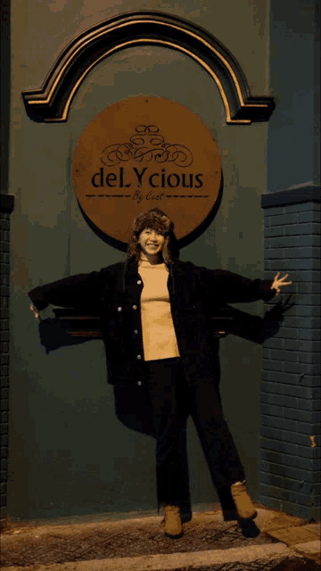 a woman is standing in front of a sign that says delycious