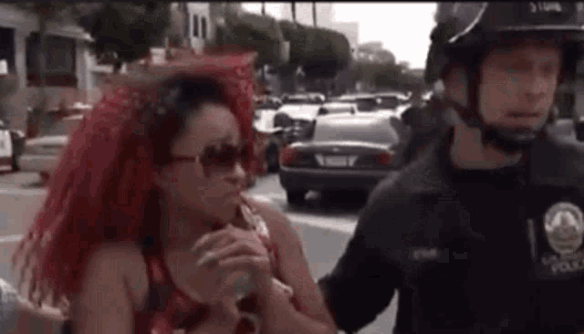 a woman with red hair is being escorted by a police officer