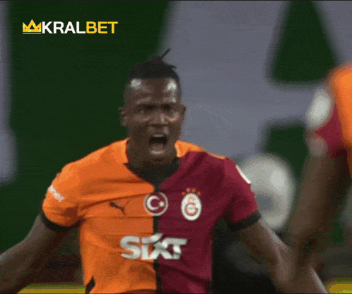 a soccer player wearing a sixt shirt stands in front of a king kralbet banner