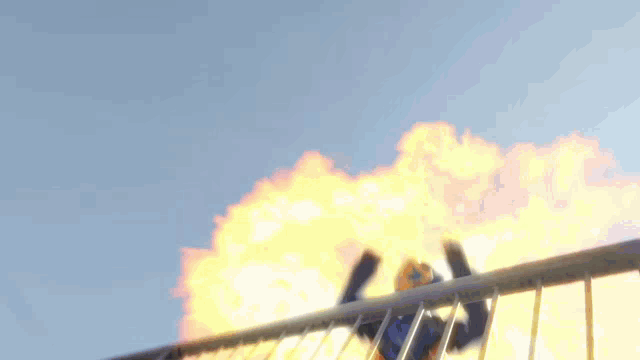 a person is standing on a fence with a huge explosion in the background