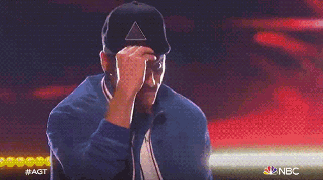 a man wearing a hat and a blue jacket is on nbc 's got talent
