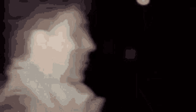 a close up of a person 's face in the dark with a blurry background .