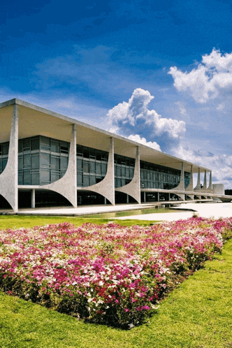a large building with flowers in front of it and a blue sky