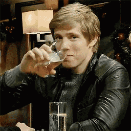 a man wearing a leather jacket is drinking from a glass
