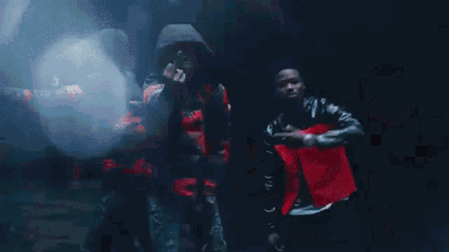 a group of people are standing in a dark room with smoke coming out of them .