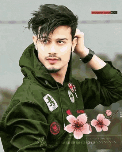 a young man wearing a green hoodie with flowers on it .