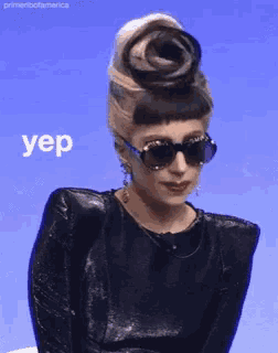 a woman wearing sunglasses and a black top has the word yep written on her face