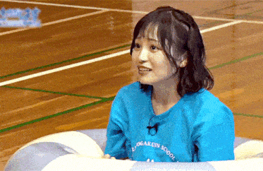 a woman wearing a blue shirt that says yogakuin school on it