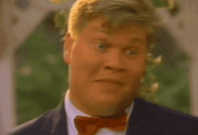a man in a suit and bow tie is making a face .