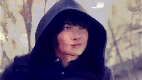 a man wearing a black hooded jacket is looking at the camera .