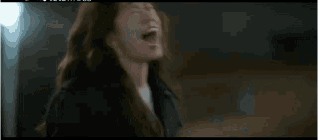 a woman in a black coat and white sneakers is walking down a street at night .