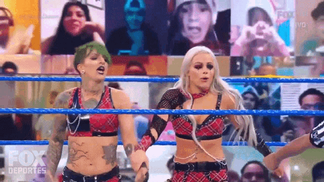 two women are holding hands in a wrestling ring .