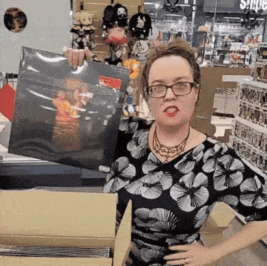 a woman in a black and white floral dress is holding a record in her hand