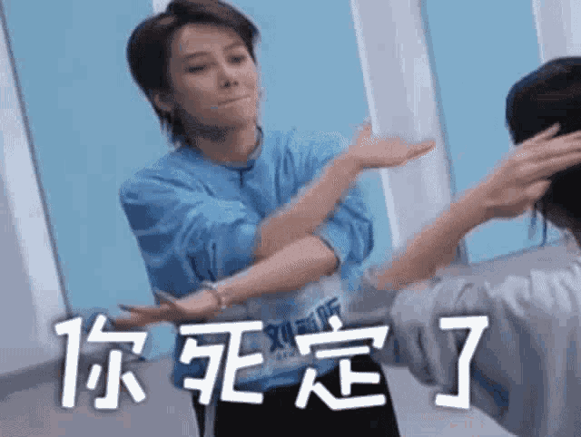 a woman in a blue shirt is standing in front of a mirror with her hands outstretched .