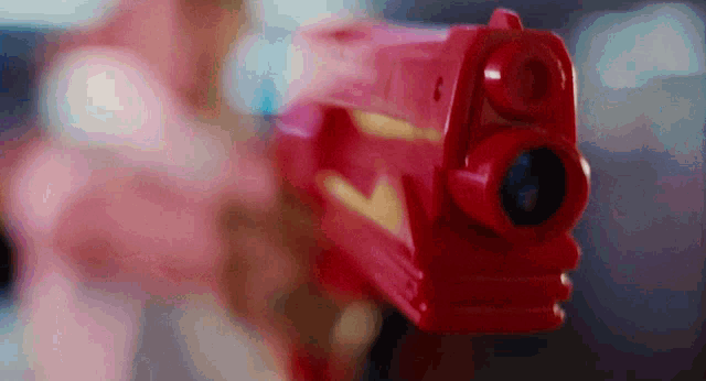 a close up of a red toy gun with a yellow arrow on the front