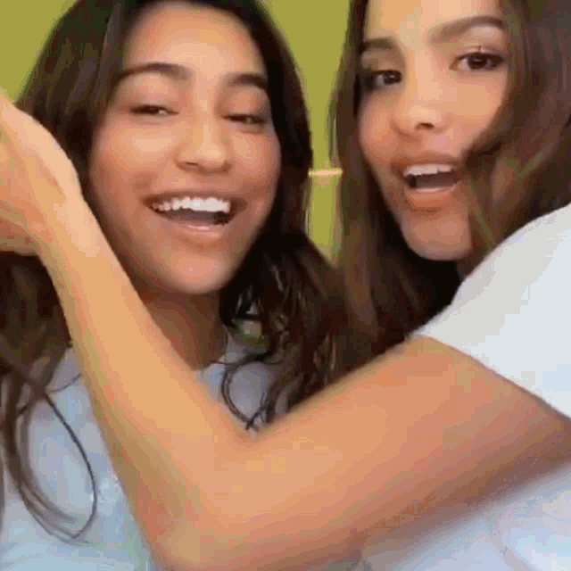 two girls are standing next to each other and smiling .