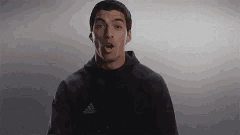 a man is wearing a black adidas hoodie and making a funny face .