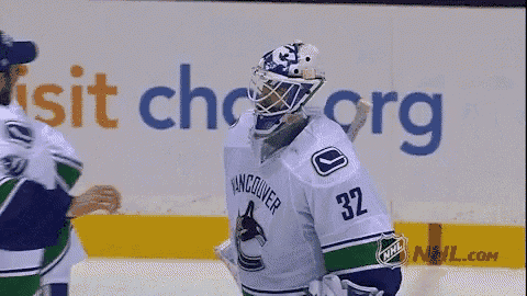 a hockey player wearing a vancouver jersey is talking to another player