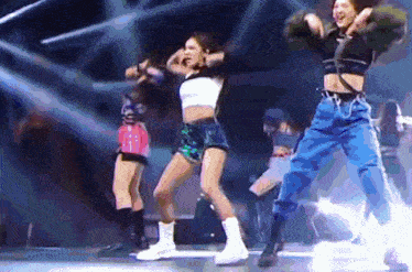three women are dancing on a stage in front of a microphone .