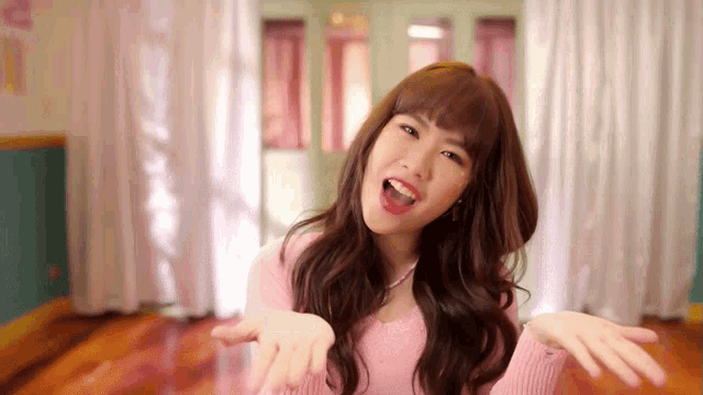a woman in a pink sweater is making a funny face with her mouth open