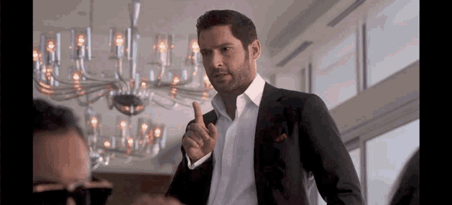 a man in a suit is giving a thumbs up sign