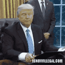 a man in a suit and tie is sitting at a desk with the website isnowillegal.com written on the bottom