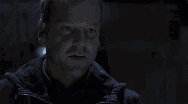a man and a woman sit at a table in a dark room talking