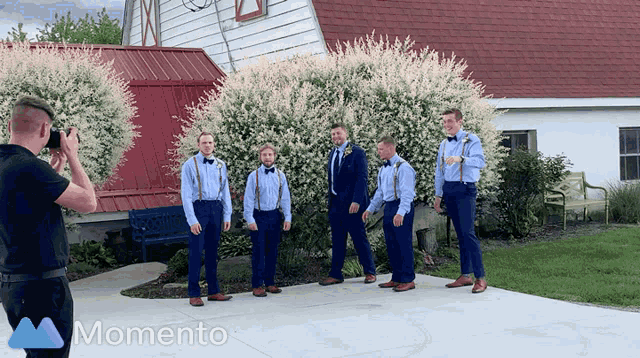 a man is taking a picture of his groomsmen in front of a barn that says momento on it